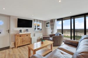 a living room with a couch and a tv at Beach House - North East Escapes in Boulmer