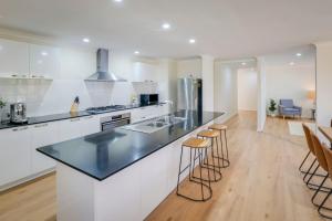 a kitchen with white cabinets and a black counter top at The Monclair Retreat - Pet Friendly Dunsborough in Dunsborough