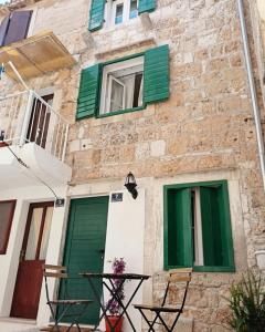 a building with green shuttered windows and a table at Apartments and rooms with parking space Komiza, Vis - 24523 in Komiža