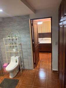 ein Badezimmer mit Toilette in einem Zimmer mit einem Bett in der Unterkunft Essential Life La Cuaba Casa de Campo Amenities in Pedro Brand