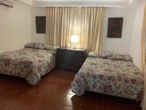 ein Hotelzimmer mit zwei Betten und einem Tisch mit einer Lampe in der Unterkunft Essential Life La Cuaba Casa de Campo Amenities in Pedro Brand