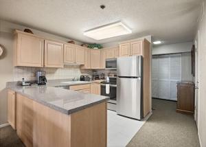 a kitchen with wooden cabinets and a stainless steel refrigerator at 3 Bedroom Gold-Rated Condo At The Base Of Aspen Mountain in Aspen