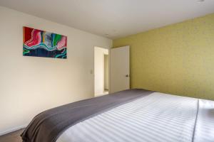 a bedroom with a bed and a painting on the wall at Highlands Apt- Lake Views- Free Parking- AC- BBQ in Queenstown