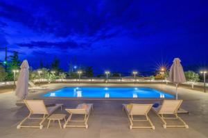 a swimming pool with chairs and umbrellas at night at Petra Luxury Rooms and Apartments in Korinthos