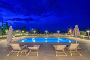 una piscina con sedie e ombrelloni di notte di Petra Luxury Rooms and Apartments a Korinthos