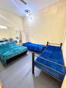 two beds in a room with blue sheets at Apart Granadero in Santiago del Estero
