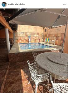 a patio with a table and chairs and a pool at Residencial Divina in Pirenópolis