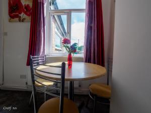 a table and chairs with a vase with a flower in a window at Newlands Lodge Deluxe Family Room 2 in Stoke on Trent +8 photos