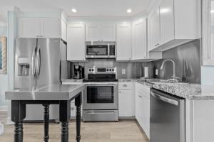 a kitchen with stainless steel appliances and white cabinets at Barefoot Ventures townhouse in Atlantic Beach +49 photos