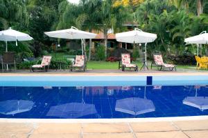 una piscina con sillas y sombrillas en Pousada Lago das Pedras, en Juiz de Fora