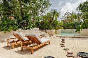 two lounge chairs on the sand next to a swimming pool at IIK Tulum Luxury Condo by Spot Rentals in Tulum