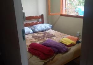 Habitación con cama y toallas de colores. en Compostela Pousada Hostel & Camping, en São Bento do Sapucaí