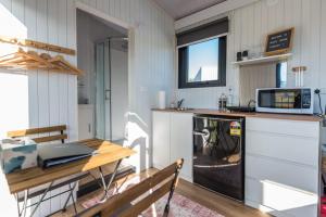 a kitchen with a table and a microwave and a stove at Black Horse Cabin 1 by Tiny Away in Parakakau