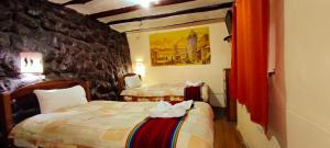a room with two beds and a stone wall at Amankay Inn in Cusco