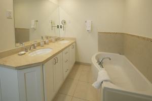 a bathroom with a tub and a sink and a bath tub at Palm Beach 110 condo in Bridgetown