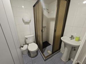 Un baño con ducha, inodoro y lavabo. en Hostal G&P, en Antofagasta