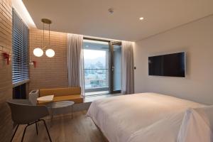 a bedroom with a bed and a desk and a tv at Cont Hotel in Busan