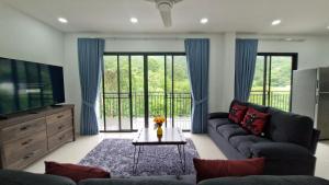 a living room with a couch and a tv at Private Valley View pool villa Phuket in Ban Klang