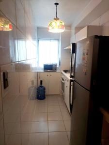 una pequeña cocina con nevera y ventana en Amplio Departamento en Centro de Concepción con estacionamiento 2D-2B, en Concepción