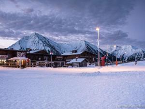 a ski lodge with snow covered mountains in the background at Appartement à Saint Lary, proche pistes, animaux admis - FR-1-296-519 in Saint-Lary-Soulan