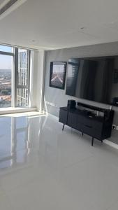 a living room with a flat screen tv and a table at Stunning Canary Wharf apartment City view in London