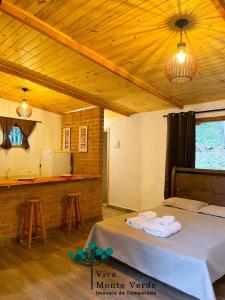 a room with a bed and a counter with a kitchen at Chalé com lareira pertinho de Monte Verde in Camanducaia