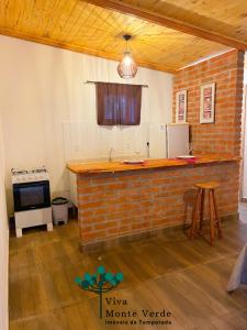 a kitchen with a brick counter in a room at Chalé com lareira pertinho de Monte Verde in Camanducaia
