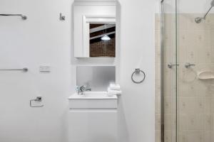 a white bathroom with a sink and a shower at Eliza Lee 3 - 3BR Apartment l Air-Con l WiFi l Double Garage in Jindabyne +13 photos