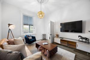 ein Wohnzimmer mit Sofa und Fernseher in der Unterkunft The Velvet Cottage in Adelaide