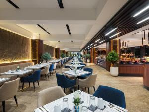 a restaurant with white tables and blue chairs at Aston Gejayan Yogyakarta Hotel & Conference Center in Yogyakarta
