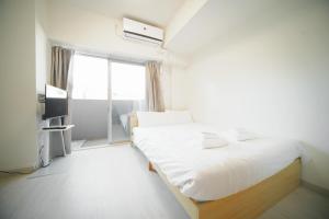 a bedroom with a white bed and a window at Color Tsuruhashi in Osaka