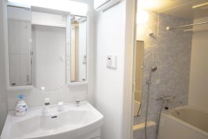 a white bathroom with a sink and a shower at Color Tsuruhashi in Osaka