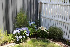 un giardino di fiori di fronte a una recinzione di Little Gem City Cottage a Invermay
