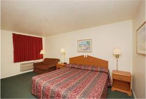 a hotel room with a bed and a chair at Summit Inn Hempstead in Hempstead