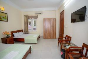 Una habitación de hotel con dos camas y un televisor. en Khách Sạn Hoàng Minh, en Sầm Sơn 6 fotos más