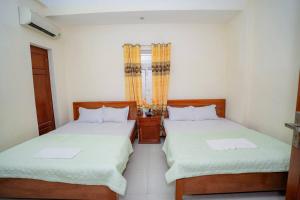 Un dormitorio con dos camas y una ventana. en Khách Sạn Hoàng Minh, en Sầm Sơn
