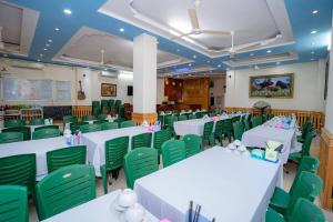 Un salón de banquetes con mesas blancas y sillas verdes. en Khách Sạn Hoàng Minh, en Sầm Sơn