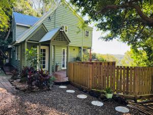 a green house with a wooden fence in front of it at Misty Valley Cottage in Mapleton