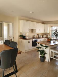 a kitchen with white cabinets and a wooden table at Cozy Connemara Family Retreat in Derroogh