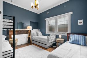 - une chambre aux murs bleus avec un lit et un lit bébé dans l'établissement Belle Escapes - Sea Glass Cottage on the Esplanade, à Henley Beach South