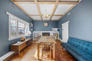 un salon avec un canapé bleu et une table dans l'établissement Belle Escapes - Sea Glass Cottage on the Esplanade, à Henley Beach South