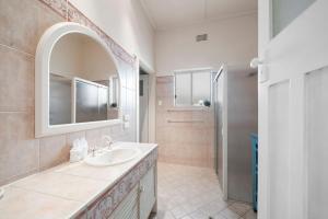 une salle de bain avec un lavabo, un miroir et une douche dans l'établissement Belle Escapes - Sea Glass Cottage on the Esplanade, à Henley Beach South 28 autres photos