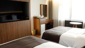 a hotel room with two beds and a flat screen tv at Commodore Hotel Gyeongju in Gyeongju
