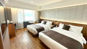 a hotel room with two beds and a window at Commodore Hotel Gyeongju in Gyeongju