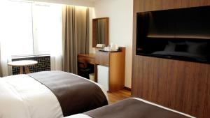 a hotel room with a bed and a flat screen tv at Commodore Hotel Gyeongju in Gyeongju