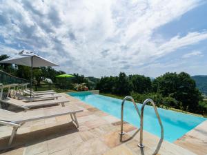 a swimming pool with chairs and an umbrella at Beautiful Apartment in Sestino with Garden in Sestino +80 photos
