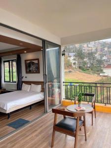 a bedroom with a bed and a table and a balcony at Happy Villa Tam Đảo in Tam Ðảo