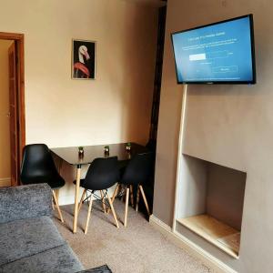 a living room with a table and a television on a wall at Comfortable House in Stoke in Stoke on Trent