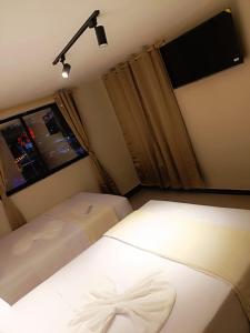 a small bedroom with two beds and a television at Hotel Golden 70 in Medellín