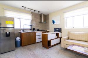 a kitchen with a refrigerator and a couch in a room at Inti Relax Garden Suite in Oranjestad